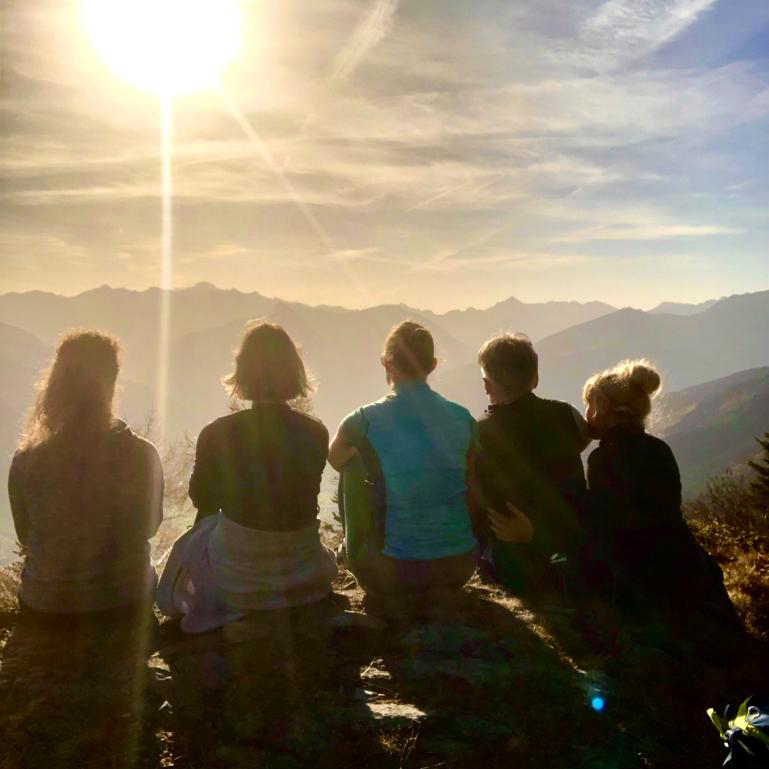 gruppe sitzt auf dem berg bei sonnenaufgang